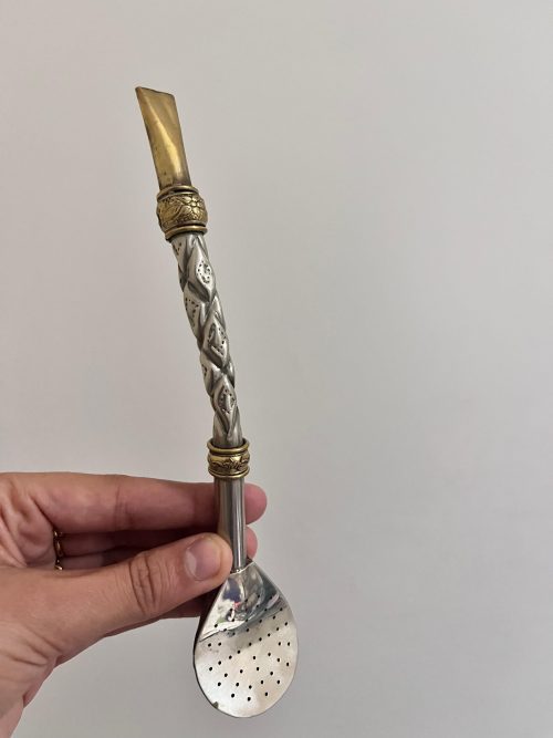 Un bombillon pico de rey en alpaca et décoré de deux virola en bronze qui sert à à filtrer l'herbe à maté et boire l'infusion
