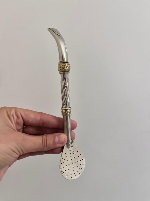 Un bombillon pico de loro en alpaca et décoré de deux virola en bronze qui sert à à filtrer l'herbe à maté et boire l'infusion