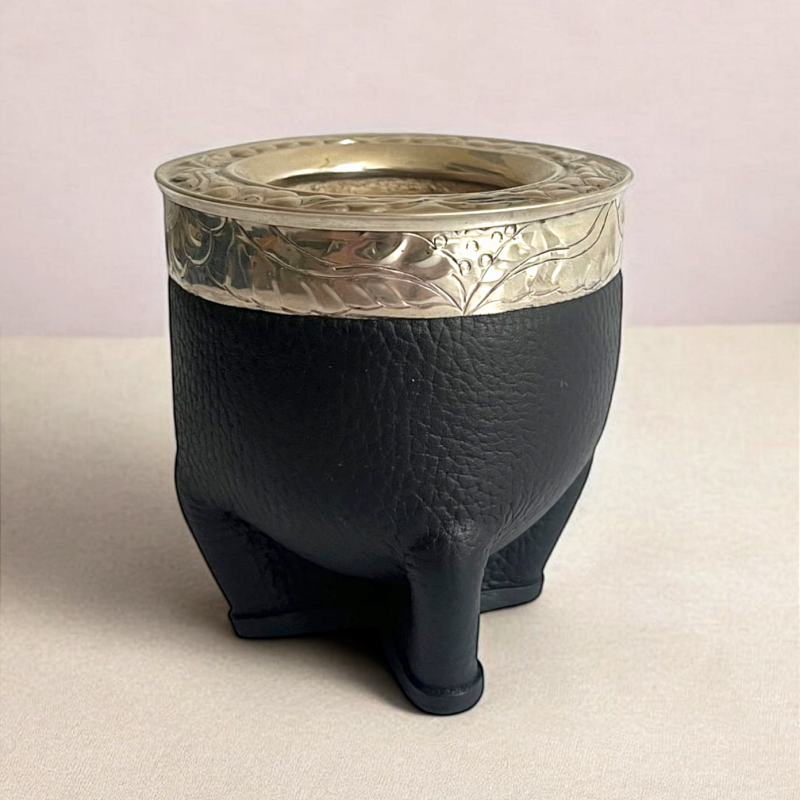 Calabaza de mate hecha a mano. Calabaza brasileña extragruesa recubierta de doble cuero negro. Está reforzada por una virola de alpaca grabada a mano.