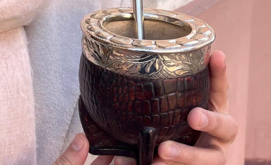 Une calebasse à maté imperial cuir croco tenu à la main et sa bombilla en alpaca