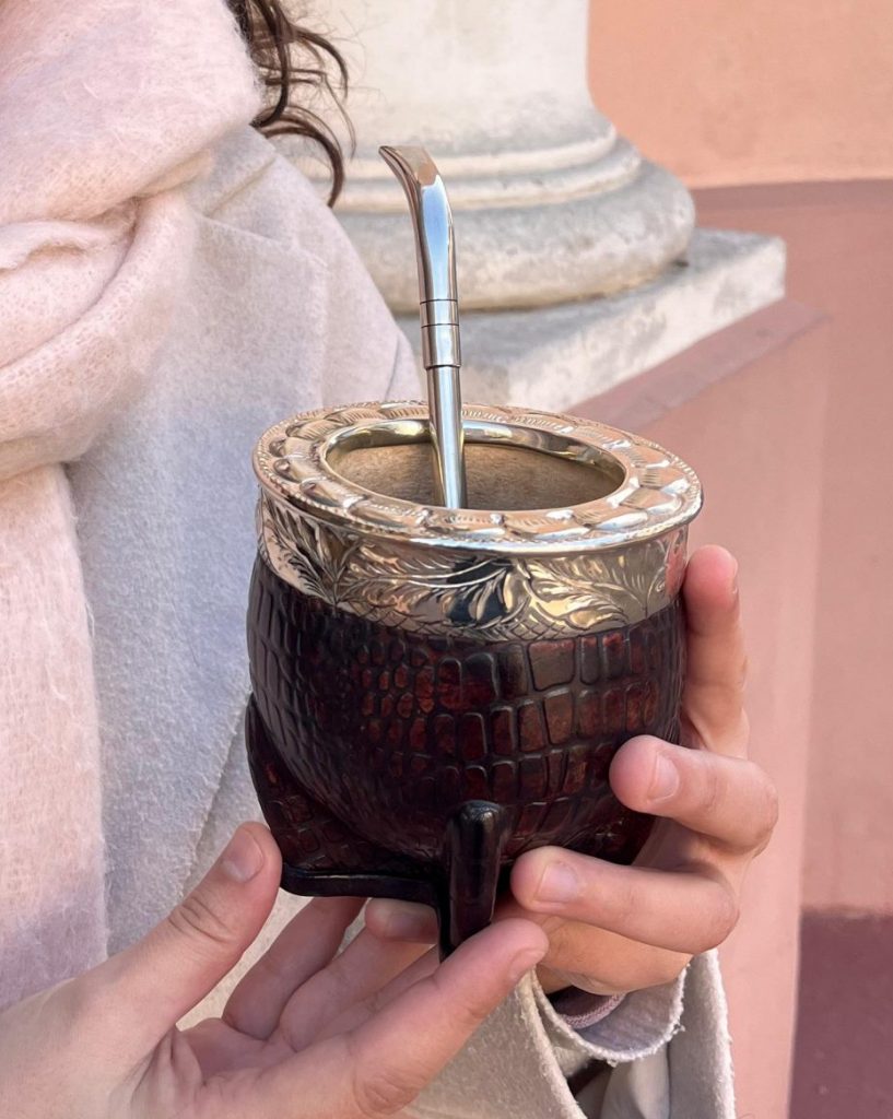 Une calebasse à maté imperial cuir croco tenu à la main et sa bombilla en alpaca