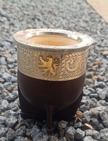 A personalised maté gourd handmade by an artisan in Uruguay. Its alpaca virola is decorated with a bronze lion.