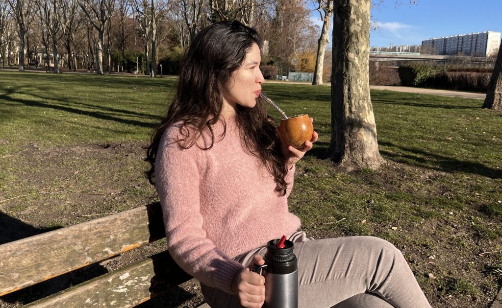 Mujer tomando mate en un banco, relajándose al aire libre